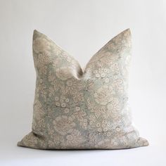 a pillow that is sitting on top of a white surface with a light blue flower pattern