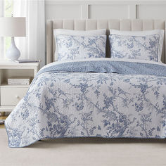 a blue and white bed in a bedroom next to a night stand with a lamp