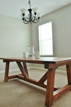 a wooden table sitting in the middle of a living room next to a chandelier