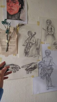 a person holding a pen in front of some drawings