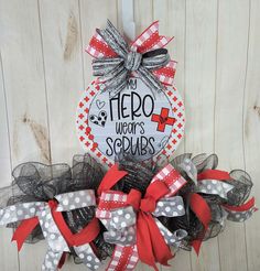 a red and white wreath with the words hero wears scrubs hanging on a wooden wall