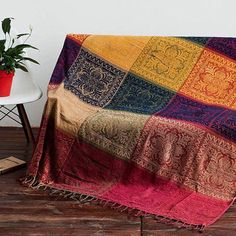 a colorful blanket sitting on top of a wooden floor next to a potted plant