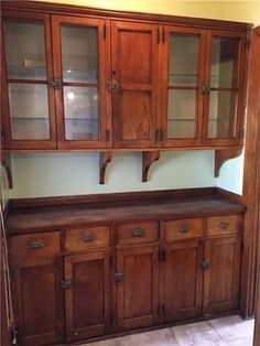 an old wooden china cabinet with glass doors and cupboards on the top, next to a tile floor