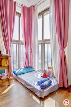 a bedroom with pink drapes and curtains on the windows