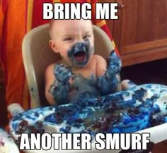 a baby sitting in a high chair with blue frosting on it's face