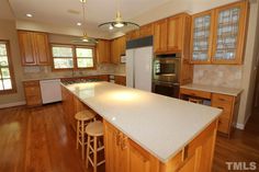 a large kitchen with wooden cabinets and white counter tops, along with an island in the middle