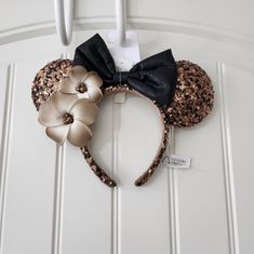 a minnie mouse ears headband with black and gold sequins is hanging on a door