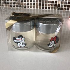 two mickey mouse coffee mugs sitting on top of a counter