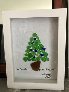 a white frame holding a green and blue glass tree