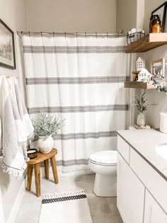 a bathroom with a white toilet sitting next to a bath tub under a shower curtain