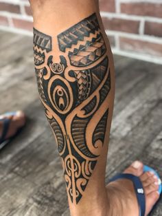 a man's leg with an intricate tattoo design on his arm and foot, in front of a brick wall