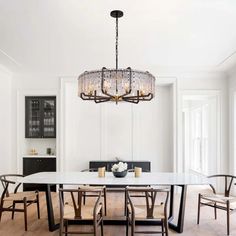 a dining room table with chairs and a chandelier hanging from the ceiling over it