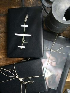 two black wrapped gifts sitting on top of a wooden table next to a potted plant