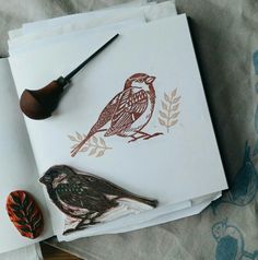 two birds sitting on top of papers next to an ink pen and stamp pad,