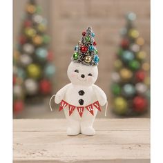 a small white snowman with a christmas tree on his head and garland around its neck