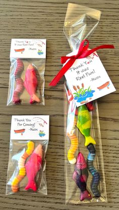 three small plastic fish packaged in cellophane and tied with a red ribbon on a wooden table