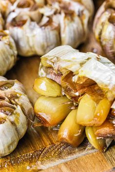 garlic and onions on a wooden cutting board with other foods in the backround