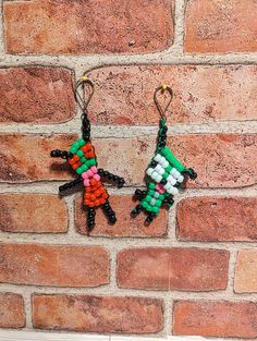 two earrings made out of legos hanging on a brick wall