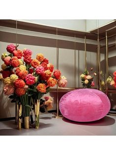 flowers are in vases next to a pink pillow on a table with mirrors behind it