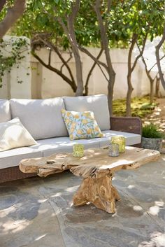 a couch sitting on top of a stone floor next to a wooden table with two cups