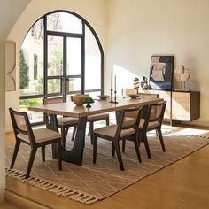 a dining room table and chairs in front of a large window with an arched doorway