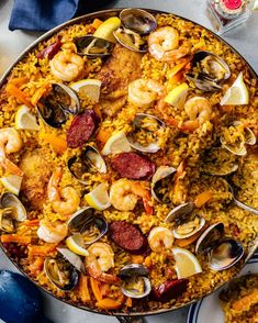 a paella with seafood, shrimp and rice on a table next to other dishes