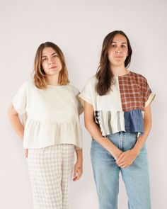 two women standing next to each other in front of a white wall