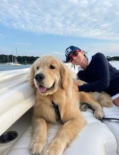 a dog is sitting on the back of a boat while a man sits next to it