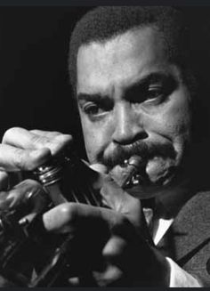 a man with a pipe in his mouth is eating something out of a glass bottle