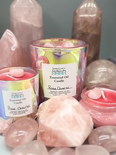 several candles and rocks on a table with some pink crystals around them, including one candle