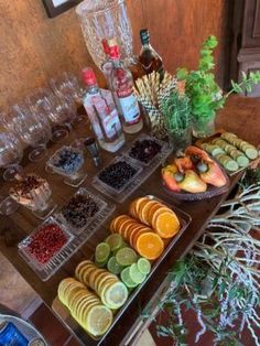 an assortment of fruits and snacks on a table with wine bottles, glasses and other items