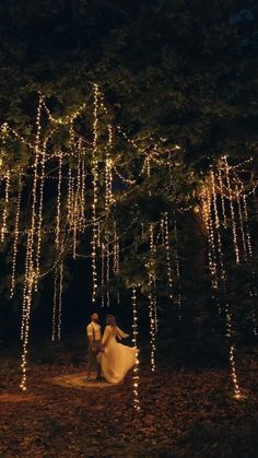 a bride and groom standing under a tree covered in lights