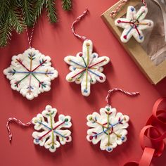 three snowflake ornaments are hanging on a red surface