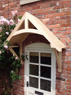 a white door and window in front of a red brick building with flowers growing on it