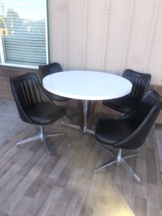 three chairs around a white table in front of a window