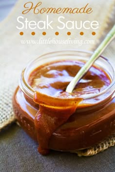 a jar filled with brown liquid sitting on top of a table next to a spoon