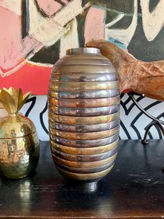 two vases sitting on top of a table next to a wall covered in graffiti