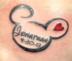 a woman's chest with a mickey mouse tattoo on it and a heart in the middle