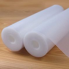 two rolls of white plastic sitting on top of a wooden table