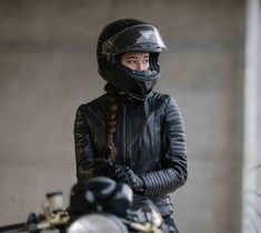 a woman wearing a helmet standing next to a motorcycle