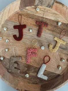 several knitted ornaments are arranged on a wooden board with beads and thread in the shape of letters