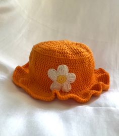 an orange crocheted hat with a white flower on it