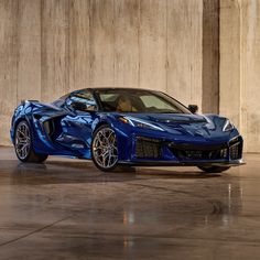 a blue sports car is parked in an empty room with concrete walls and flooring