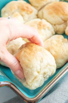 a person picking up some biscuits from a blue dish