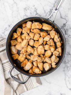 a skillet filled with chicken on top of a marble counter