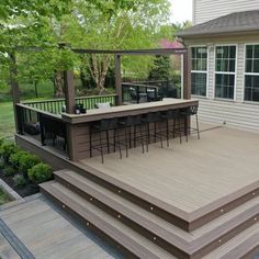 a deck with bar stools on it in front of a house