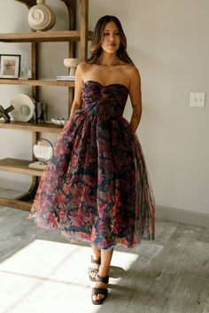 The Mariah Navy Floral Tulle Midi Dress is a romantic and elegant statement piece. Featuring tulle fabric with a stunning floral print in navy, rust, red, and mustard, this dress boasts a flattering A-line silhouette and a midi length that adds a graceful touch. The twist sweetheart neckline and strapless design create a feminine and timeless look, while the navy lining ensures comfort. A monochrome back zipper with hook closure provides a seamless fit, making the Mariah dress perfect for specia Fitted Multicolor Tulle Dress, Vintage Tulle Skirt Dress For Party, Vintage Tulle Dress For Party, Fall Party Dress With Tulle Skirt, Fall Wedding Floral Print Dress, Fall Tulle Skirt Dress, Red Dress For Fall Garden Party, Tulle Midi Dress, White Bodycon Dress