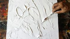 a person is painting with white paint on a canvas