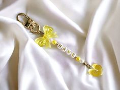 a keychain with yellow flowers and pearls on white satin fabric, that says made in heaven