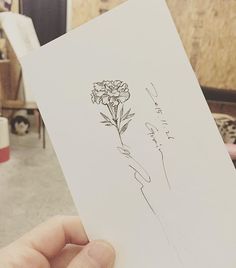 a person holding up a piece of paper with a drawing of a flower on it